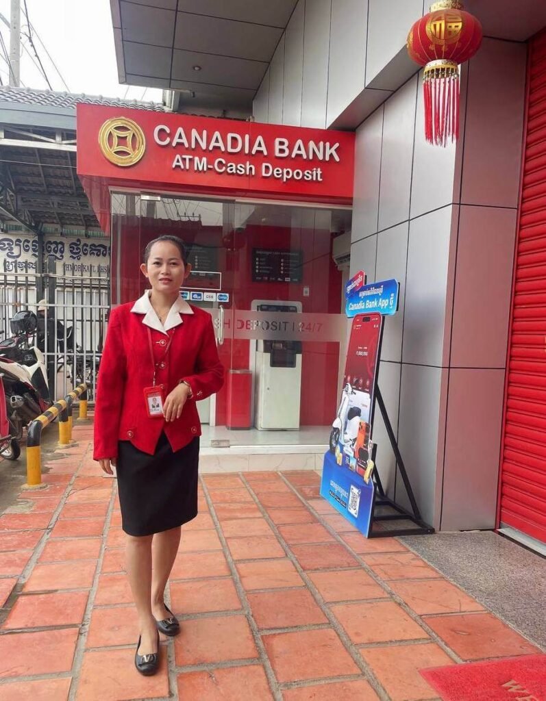 A professional woman standing outside Canadia Bank in a red uniform, representing the working mom behind the Sprout Upward blog.