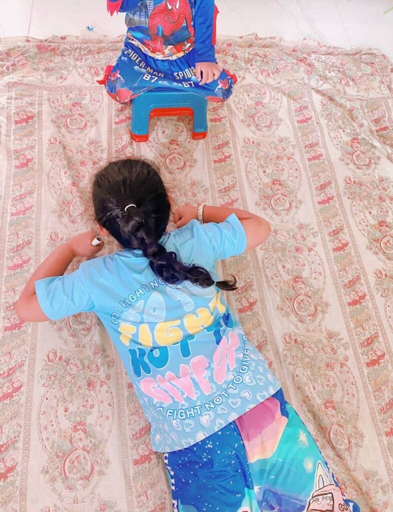 A child viewed from above doing a commando crawl on their elbows and stomach across a large patterned blanket spread on the floor.