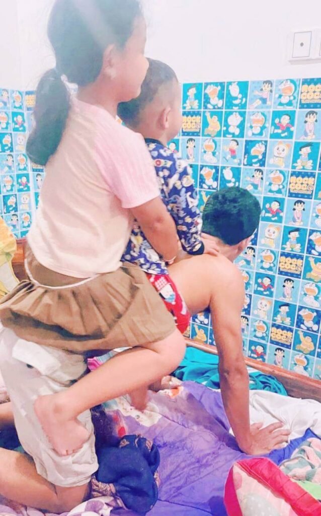 A father playfully giving his children a "cattle ride" on his back in the bedroom to laugh and reset after using technology.