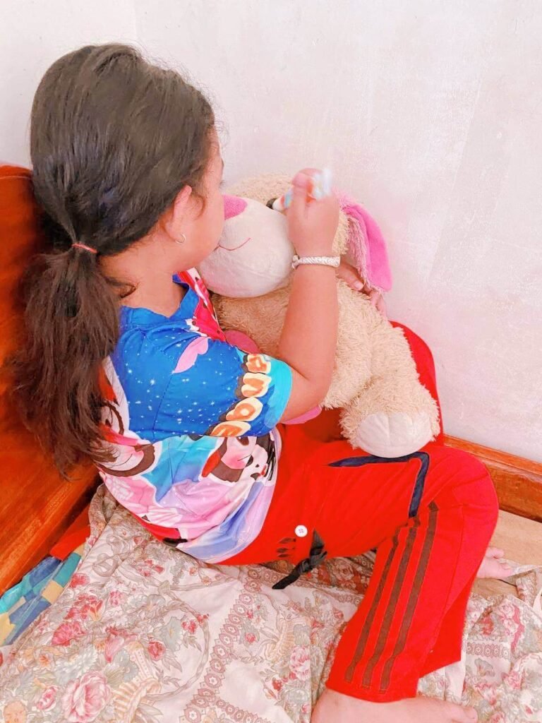 A young girl sitting quietly in a corner holding a stuffed dog, taking time to calm down.