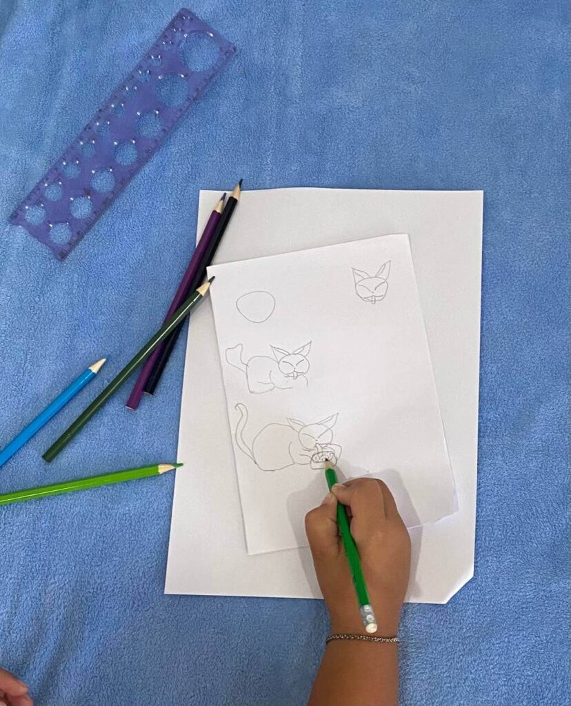 Final step of drawing a hungry cat eating from a small bowl, sketched by a child to show beginner-friendly animal drawing techniques.