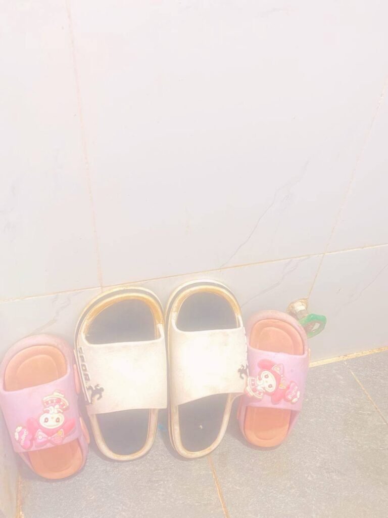 Two pairs of children’s used slides, one pink with cartoon characters and one white, neatly lined up against a white tiled bathroom wall.